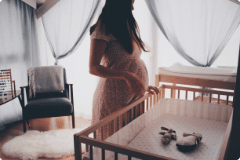 Pregnant woman standing beside a baby bed